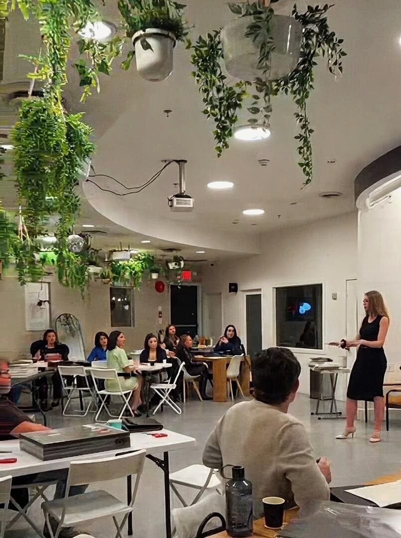 Kimberley Karstunen leading a workshop in person, speaking to a seated group.